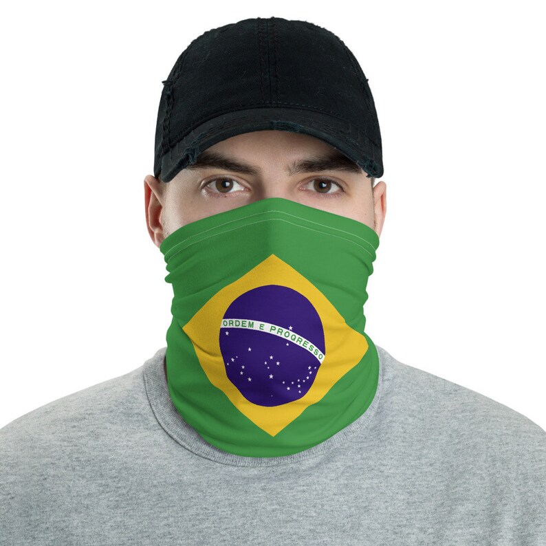 Pu&ograve; includere: Una maschera facciale verde, gialla e blu con la bandiera brasiliana stampata su di essa. La bandiera presenta un cerchio blu con stelle bianche e il testo "ORDEM E PROGRESSO".