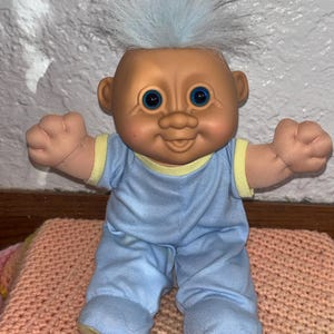 Puede incluir: Un letrero de madera hecho a mano con el texto "Welcome" en una fuente juguetona. El letrero presenta un fondo blanco desgastado y un borde marrón oscuro, ideal para una puerta de entrada. Mide aproximadamente 30 cm de ancho.