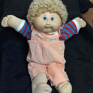 Muñeco Cabbage Patch Kids niño, cabello rubio, un diente, overol color melocotón