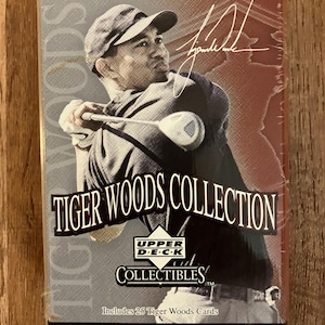 Puede incluir: Una lata coleccionable con Tiger Woods. La lata tiene una imagen de Tiger Woods balanceando un palo de golf. El texto en la lata dice "TIGER WOODS COLLECTION" y "PREMIERE EDITION". Incluye 25 cartas de Tiger Woods y una tarjeta conmemorativa de 8,89 cm x 12,7 cm.