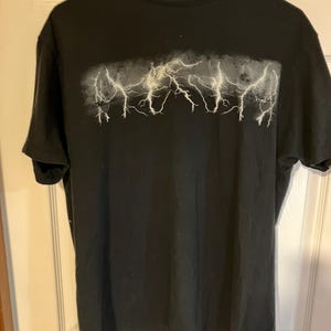 May include: Black t-shirt with a white lightning bolt graphic.