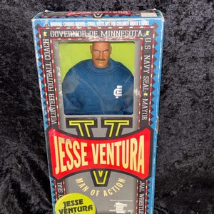 May include: A vintage Jesse Ventura action figure in its original box. The box features a red and yellow design with the text "Jesse Ventura Man of Action" and "Governor of Minnesota." The figure is wearing a blue shirt. For ages 5 and up.