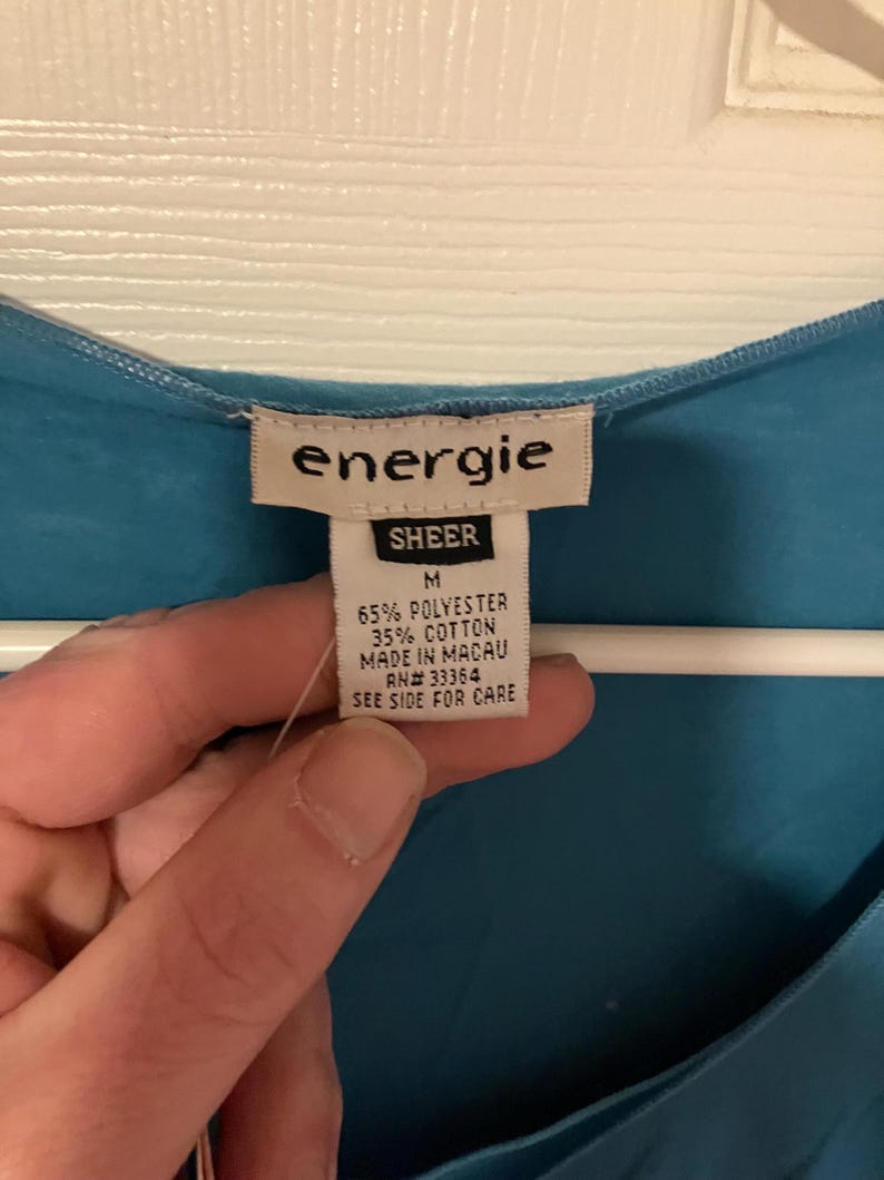 May include: A blue sheer top with a white tag that reads "energie SHEER M 65% POLYESTER 35% COTTON MADE IN MACAU AN# 33364 SEE SIDE FOR CARE"