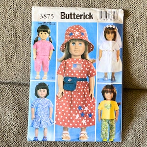May include: A Butterick 3875 sewing pattern envelope featuring illustrations of dolls wearing various outfits, including a red and white polka dot dress with a matching hat, a pink two-piece set, a white dress with a veil, and a yellow shirt with pants.
