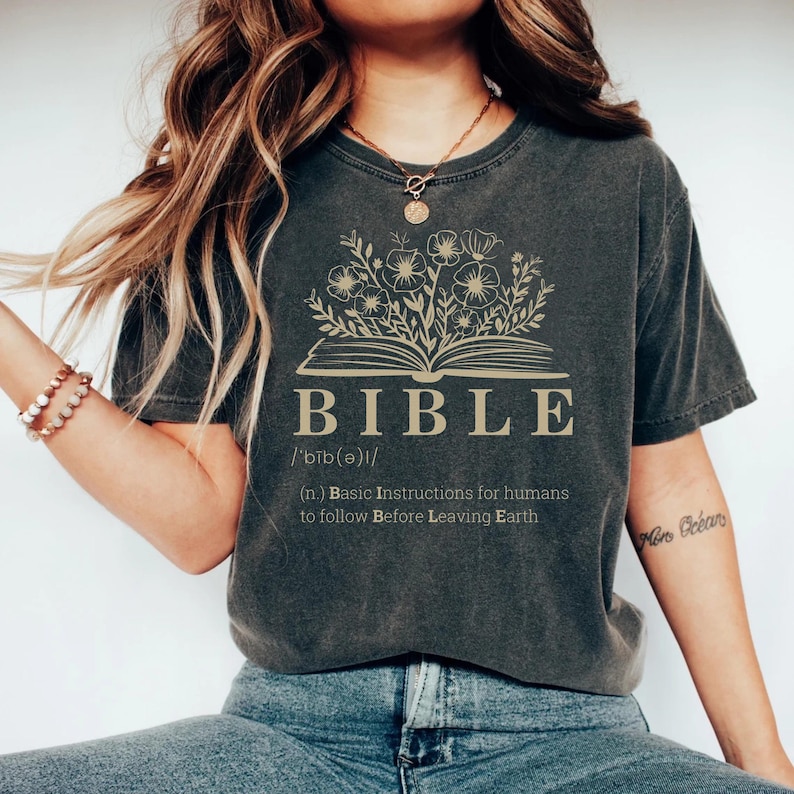 A line-art illustration of an open book with flowers growing from its pages. Hand‑lettered open Bible motif with floral sprigs above an open book and centered text acronym BIBLE with dictionary‑style definition phrase
