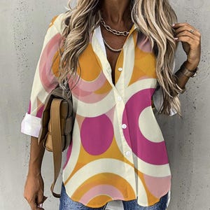 May include: A long-sleeved button-down shirt with a white background and a geometric pattern of pink, orange, and yellow circles.