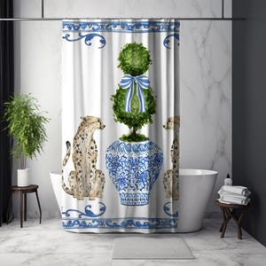 May include: White shower curtain with a blue and white border and design. The curtain features a watercolour illustration of a cheetah, a topiary tree with a blue and white striped bow, and a blue and white vase.