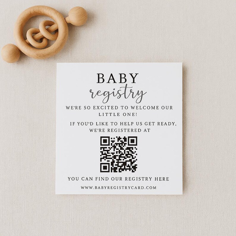 May include: A square white baby registry card with the word "BABY registry" in black script. The card includes a QR code and the text "WE'RE SO EXCITED TO WELCOME OUR LITTLE ONE!" and "YOU CAN FIND OUR REGISTRY HERE". A wooden baby rattle is in the background.