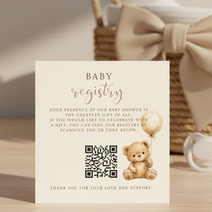 Peut inclure: Carte de registre de bébé avec le mot « BABY registry » en écriture élégante. La carte présente un ours en peluche tenant un ballon, un code QR et du texte. Une sucette et un panier avec un nœud sont en arrière-plan.