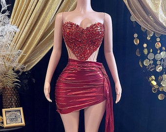 May include: A red, strapless, heart-shaped, sequined top with a matching red skirt. The skirt has a high waist and a long, flowing train.