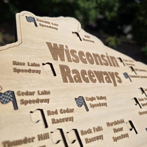 May include: Wooden sign featuring the words "Wisconsin Raceways" in a bold font. The sign is shaped like the state of Wisconsin and includes the names of various speedways, along with checkered flag graphics.