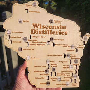 May include: Wooden map of Wisconsin distilleries, laser-cut with a light brown finish. The map features the state outline with distillery names and barrel icons. The text "Wisconsin Distilleries" is prominently displayed.