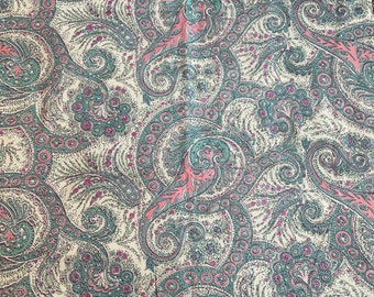 May include: Close-up of a fabric with a repeating paisley pattern. The design features swirling, teardrop-shaped motifs in shades of teal, pink, and purple against a cream-colored background. The fabric has a vintage aesthetic.