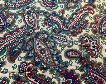 May include: Close-up of a fabric with a repeating paisley pattern. The design features large, ornate teardrop shapes in shades of burgundy, teal, and navy blue, set against a cream-colored background. The fabric has a vintage or retro aesthetic.