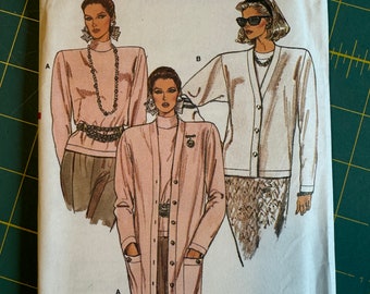 May include: A vintage sewing pattern titled "Very Easy Very Vogue" featuring illustrations of women's fashion. The pattern number is 9668, with sizes 14-16-18. The designs include a long cardigan, a blouse, and a skirt.