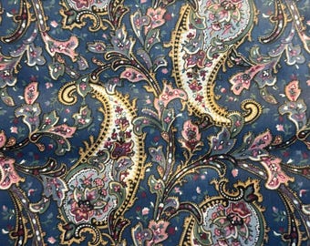 May include: Close-up of a fabric with a detailed paisley pattern. The design features a dark blue background with intricate floral and swirling motifs in shades of pink, gold, and gray. The overall aesthetic is ornate and vintage.