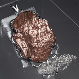 May include: A pendant featuring a large, irregular, textured copper-colored nugget set within a polished silver-toned metal frame. The pendant is attached to a silver-toned link chain with a lobster claw clasp and a small tag marked ITALY.