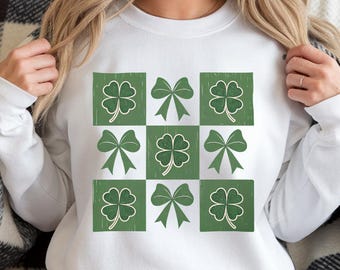 Puede incluir: Sudadera blanca con un patrón de cuadros verdes con tréboles de cuatro hojas y lazos.