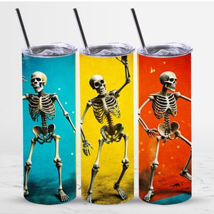 Pode incluir: Três copos de aço inoxidável com fundos de cores diferentes e um esqueleto dançando em cada um. Os copos são azuis, amarelos e laranja.