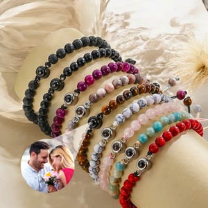 May include: A set of eight bracelets with different colored beads and a hidden photo locket charm. The bracelets are made of lava rock, amethyst, rose quartz, tiger's eye, white agate, turquoise, and red coral.
