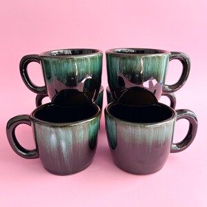 Peut inclure: Ensemble de six tasses en céramique noire et verte avec une finition émaillée. Les tasses ont une forme arrondie et une poignée sur le côté.