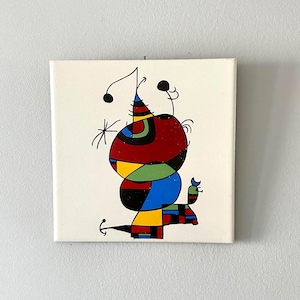 May include: A square canvas painting featuring a central abstract figure composed of bold black outlines filled with primary colors including red, blue, yellow, and green. The composition includes geometric shapes, curved lines, and small circular accents.