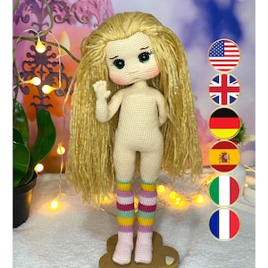 May include: A crocheted doll with long blonde hair, wearing pink and yellow striped socks. The doll has green eyes and a light pink blush on its cheeks. The doll is standing on a wooden base.