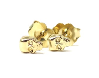 May include: A pair of gold skull stud earrings. The earrings are small and delicate, with a simple design.
