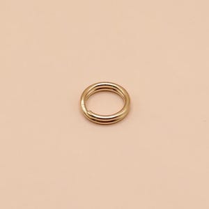 May include: A gold-colored metal jump ring. The ring is round and has a smooth surface.