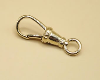 May include: A gold-colored swivel clasp with a spring-loaded hook and a small circular ring. The clasp is designed to rotate and is likely used for attaching items such as keychains or straps. The metal has a shiny finish.