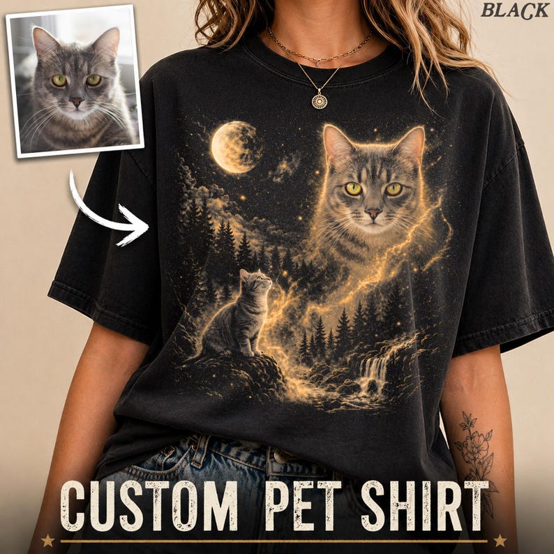 May include: Black t-shirt featuring a custom pet portrait. The design includes a large cat image with yellow eyes, a smaller cat, a moon, and a waterfall. The words "CUSTOM PET SHIRT" are printed at the bottom.