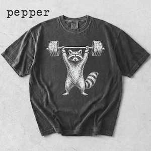 Pode incluir: T-shirt cinzenta escura com uma ilustração branca de um guaxinim a levantar uma barra. O guaxinim é retratado com os braços levantados, segurando a barra acima da cabeça. A palavra "pepper" está impressa no canto superior esquerdo.
