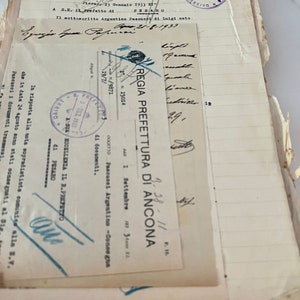 May include: A black and white stamp with the text "REGIA PREFETTURA DI ANCONA" and the date "1 Settembre 1933" in Italian. The stamp is on a white piece of paper with handwritten text.