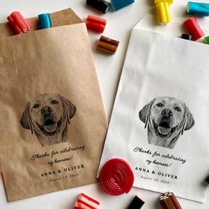 May include: Two brown paper favour bags with a black and white illustration of a dog on each. The text on the bags reads "Thanks for celebrating my hoomans! Anna & Oliver August 19, 2025".