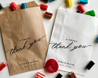 May include: Two brown and white paper bags with black script that says "A Sweet Thank You" and the names "Anna & Oliver" and the date "August 19, 2025".