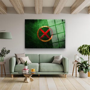 Könnte beinhalten: Gerahmtes Wandbild mit grünem, strukturiertem Hintergrund und einem goldfarbenen Kreis mit einem roten 'X' in der Mitte. Das Kunstwerk wird über einem grünen Sofa in einem Wohnzimmer gezeigt. Das Zimmer hat Holzbalken.