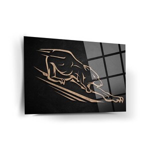 Könnte beinhalten: Gerahmter Kunstdruck mit einer stilisierten, hellbraunen Pantherdarstellung vor einem strukturierten schwarzen Hintergrund. Der Panther ist in Bewegung dargestellt, mit langgestrecktem Körper und offenem Maul. Das Kunstwerk wird vor weißem Hintergrund präsentiert.