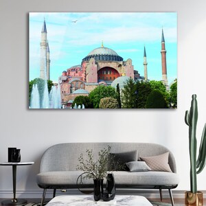 May include: A framed print of the Hagia Sophia in Istanbul, Turkey. The image shows the iconic building with its large dome, minarets, and surrounding trees and fountains, under a blue sky.