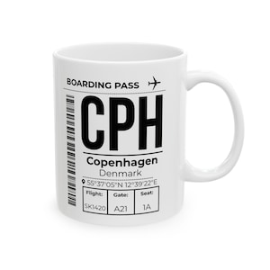 Puede incluir: Una taza de cerámica blanca con un diseño gráfico negro de una tarjeta de embarque para Copenhague, Dinamarca. El texto incluye CPH, las coordenadas 55°37'05"N 12°39'22"E, vuelo SK1420, puerta A21 y asiento 1A, junto a un código de barras.