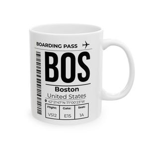 May include: A white ceramic mug featuring a black graphic design resembling a boarding pass for Boston, Massachusetts. The text includes BOARDING PASS, BOS, Boston, United States, coordinates 42°21'47"N 71°00'23"W, and flight details VS12, E15, 1A.