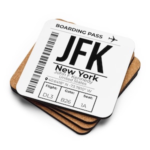 May include: A stack of square coasters with rounded corners, featuring a white top surface printed with a black boarding pass design for JFK New York. The text includes John F Kennedy, United States, coordinates, and flight details DL3, B26, 1A.