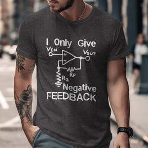 Puede incluir: Una camiseta gris oscura con un gráfico blanco de un diagrama de circuito eléctrico y el texto "I Only Give Negative Feedback".