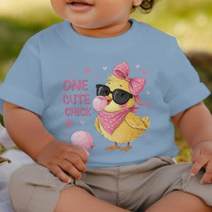 Op de afbeelding: Een lichtblauw baby t-shirt met een cartoon kuiken dat een zonnebril en een roze bandana draagt. De tekst "One Cute Chick" staat op het shirt gedrukt.
