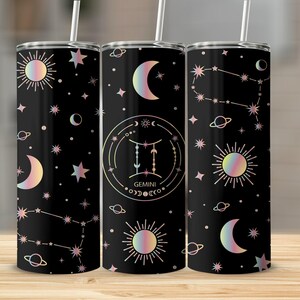 Op de afbeelding: Drie zwarte roestvrijstalen bekers met hemelse ontwerpen. Elke beker heeft een sterrenbeeldpatroon, zonnen, manen en sterren in iriserende kleuren. De middelste beker heeft een Tweelingen-dierenriemteken.