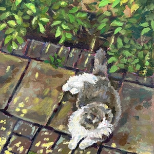 May include: An oil painting depicts a fluffy gray and white cat lounging on a brick patio. The cat is positioned near a lush green bush. The artwork is rendered in warm tones, with visible brushstrokes adding texture and depth to the scene.