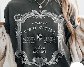 May include: Dark gray sweatshirt featuring the title "A Tale of Two Cities" in a decorative frame. The text includes quotes from the novel by Charles Dickens. The sweatshirt is a comfortable, casual style.