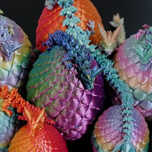Pu&ograve; includere: Una collezione di sculture a tema drago, colorate e a forma di uovo. Le sculture presentano squame e draghi dettagliati. I colori includono blu, verde, arancione e viola, creando un effetto arcobaleno. I draghi sono finemente scolpiti.