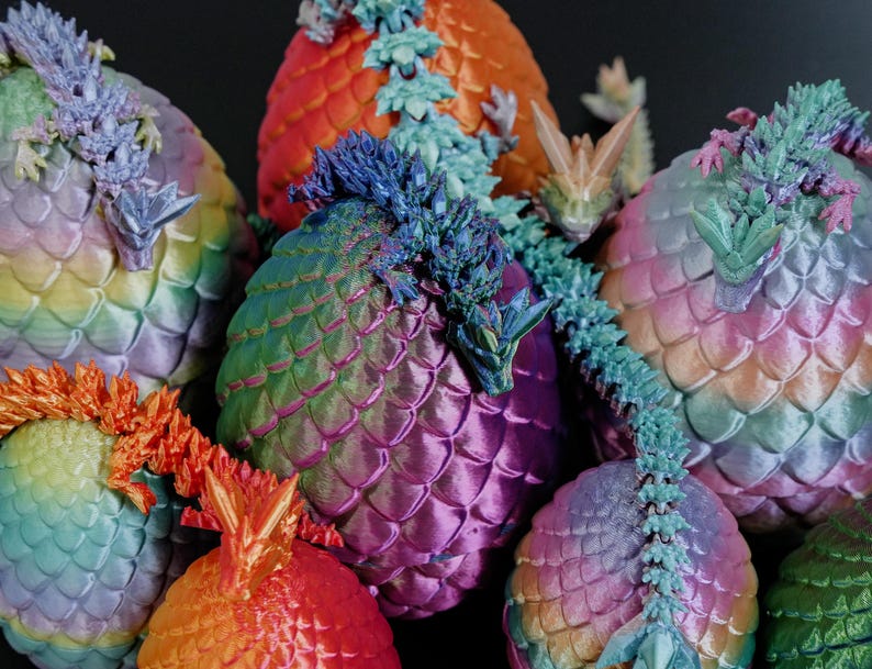 Pu&ograve; includere: Una collezione di sculture a tema drago, colorate e a forma di uovo. Le sculture presentano squame e draghi dettagliati. I colori includono blu, verde, arancione e viola, creando un effetto arcobaleno. I draghi sono finemente scolpiti.