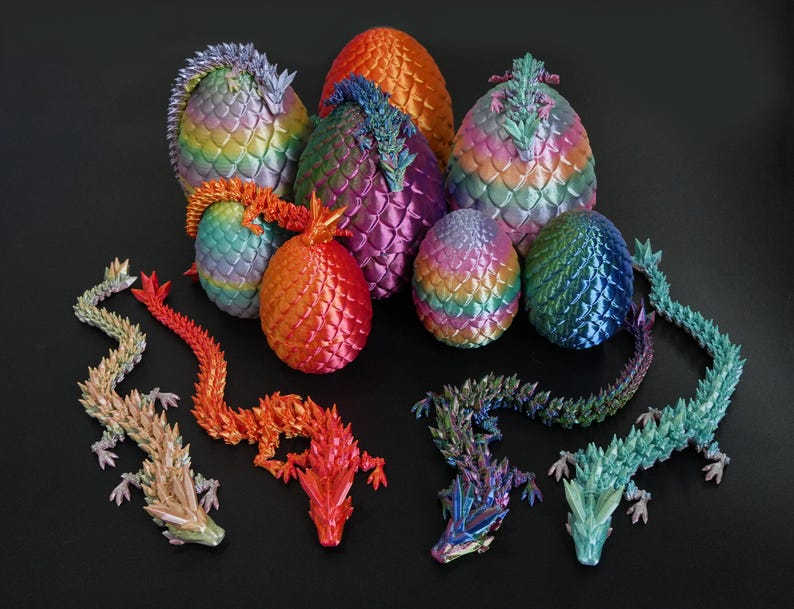 Pu&ograve; includere: Una collezione di uova e draghi colorati. Le uova presentano una texture a scaglie e variano dall'arancione al viola e al blu. I draghi sono in tonalit&agrave; di rosso, arancione e verde, su sfondo nero.