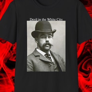 Puede incluir: Camiseta negra con un retrato vintage en blanco y negro de un hombre con bombín y traje. El texto "Devil in the White City" está encima del retrato. El fondo tiene un diseño rojo y negro arremolinado.